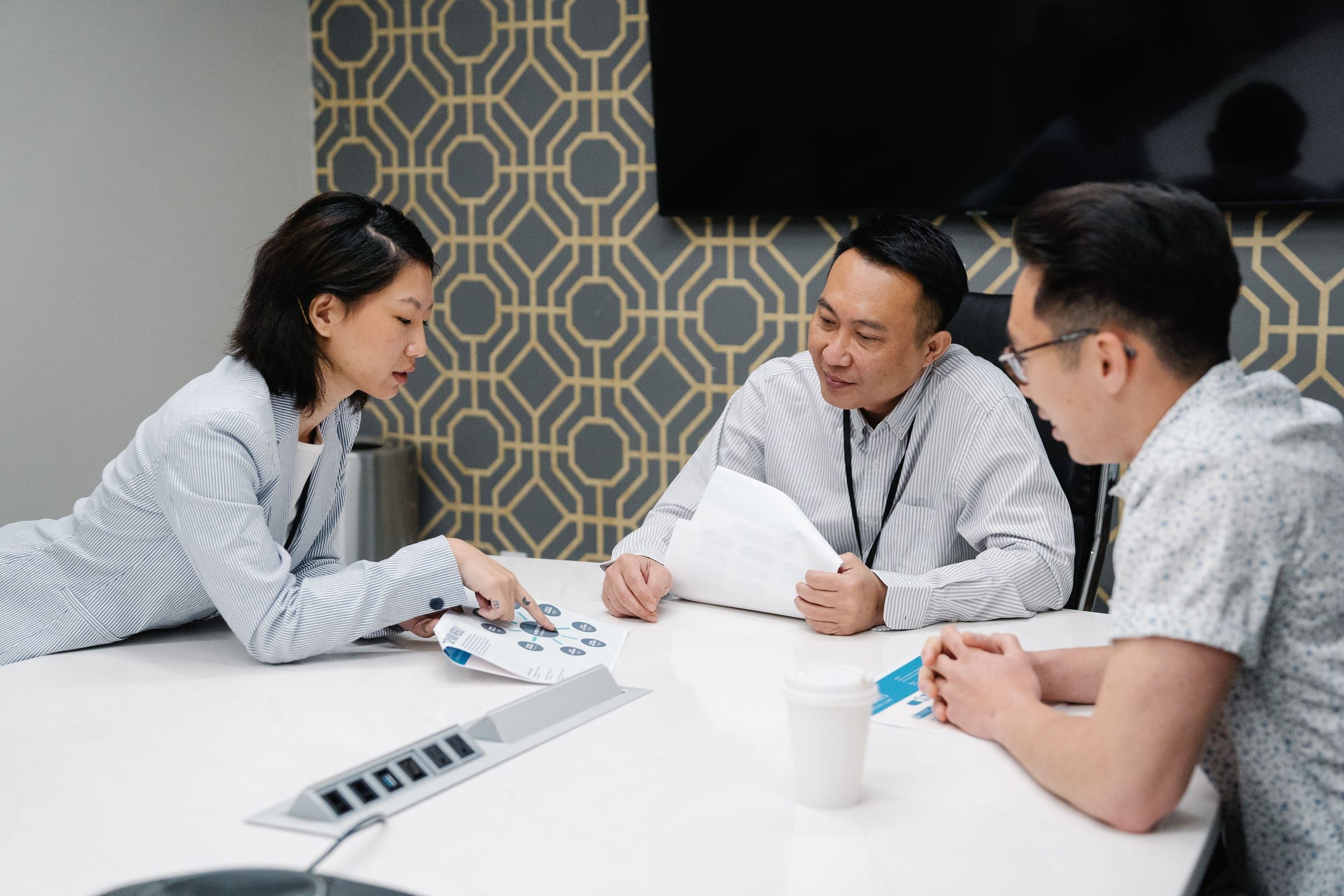 Three colleagues reviewing a printed report together at a meeting table
