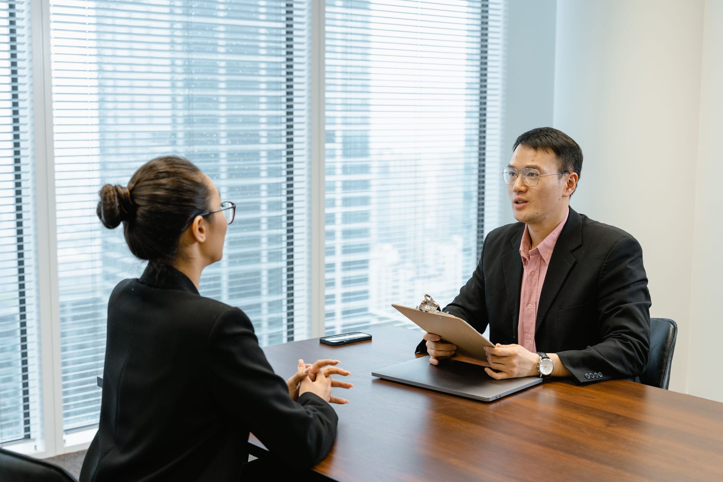 Interview between two professionals at a meeting table in a high-rise office