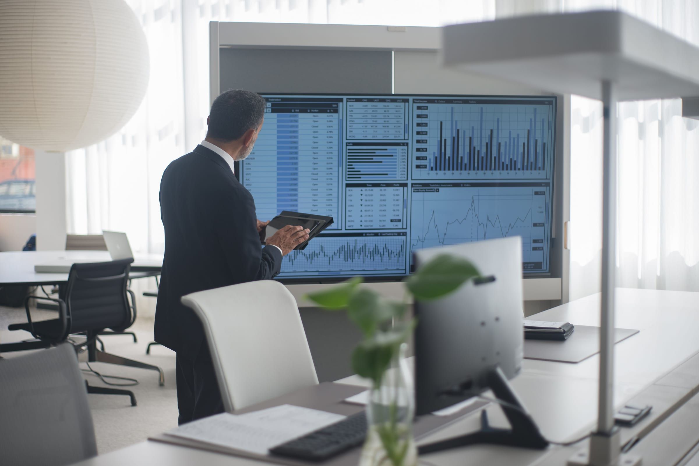 Executive reviewing financial charts on a large screen in a bright office